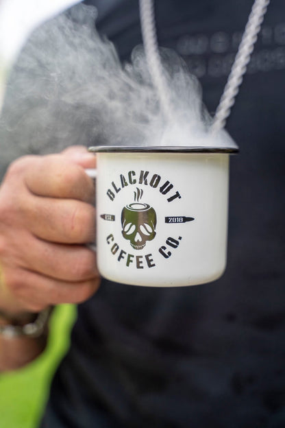 Person holding a 'Blackout Coffee Co.' mug with steam rising from it.