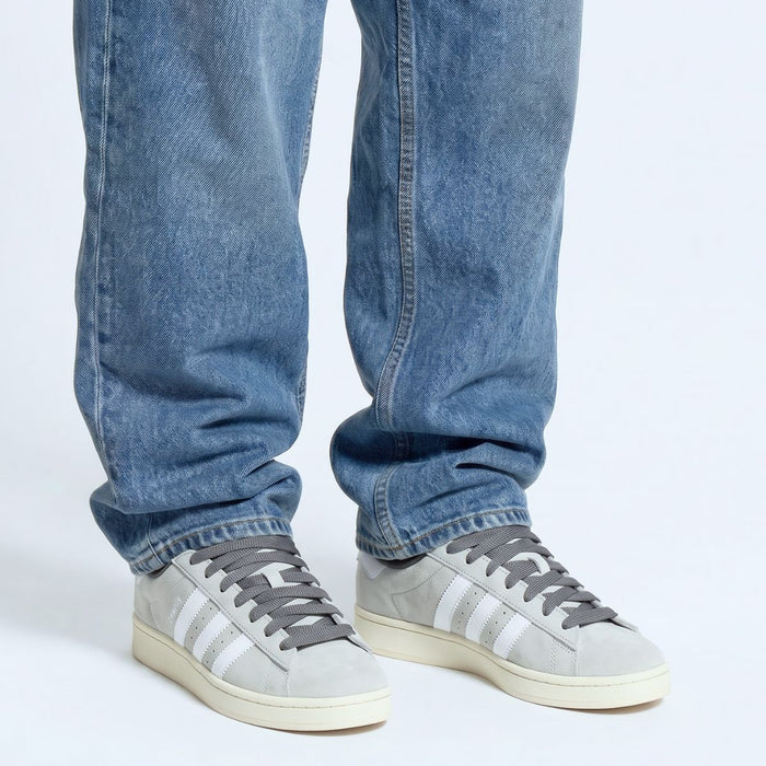 Model wearing grey Adidas Campus 00s with dark grey 15mm wide replacement laces in a clean studio setting by Kicks Shoelaces