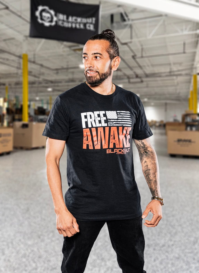 Man wearing a black t-shirt with 'Free Awake' text in a warehouse setting