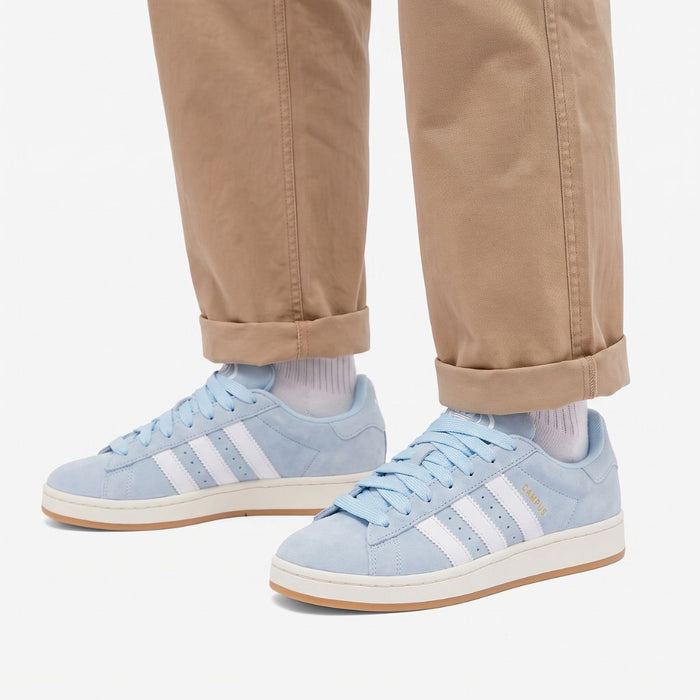 Model wearing Clear Sky Gum Adidas Campus 00s with light blue 15mm wide replacement laces in a clean studio setting by Kicks Shoelaces