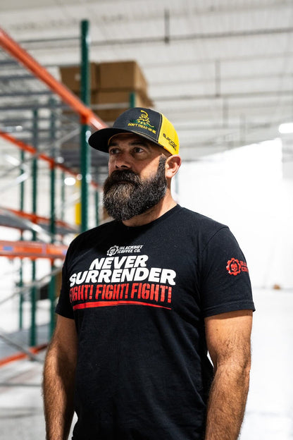 Man wearing a black t-shirt with 'Never Surrender Fight Fight Fight' text in a warehouse setting.