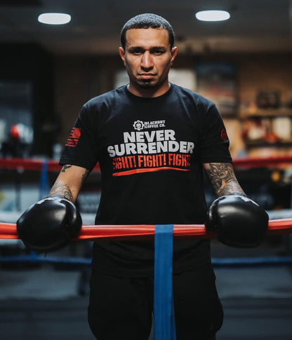 Person wearing a black t-shirt with 'Never Surrender Fight Fight Fight' text, holding boxing gloves in a gym.