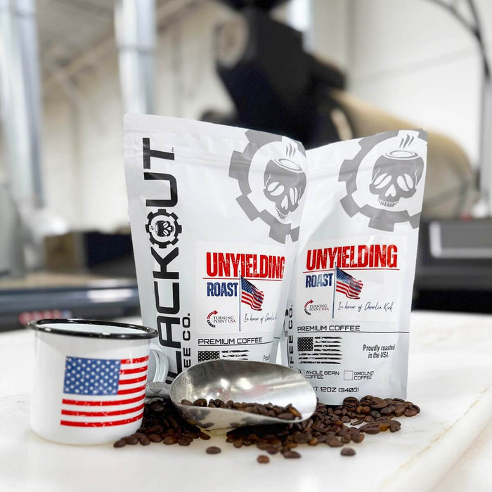 Two bags of 'Unyielding Roast' coffee with a mug in front of roaster.