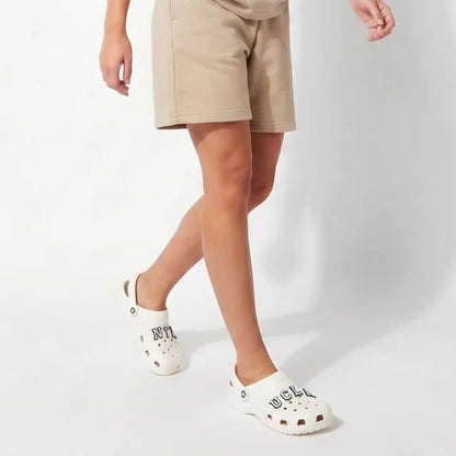 Young female model wearing casual streetwear styling with Crocs and varsity letter charms by Kicks Shoelaces